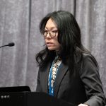 Speaker at podium addressing audience during conference.