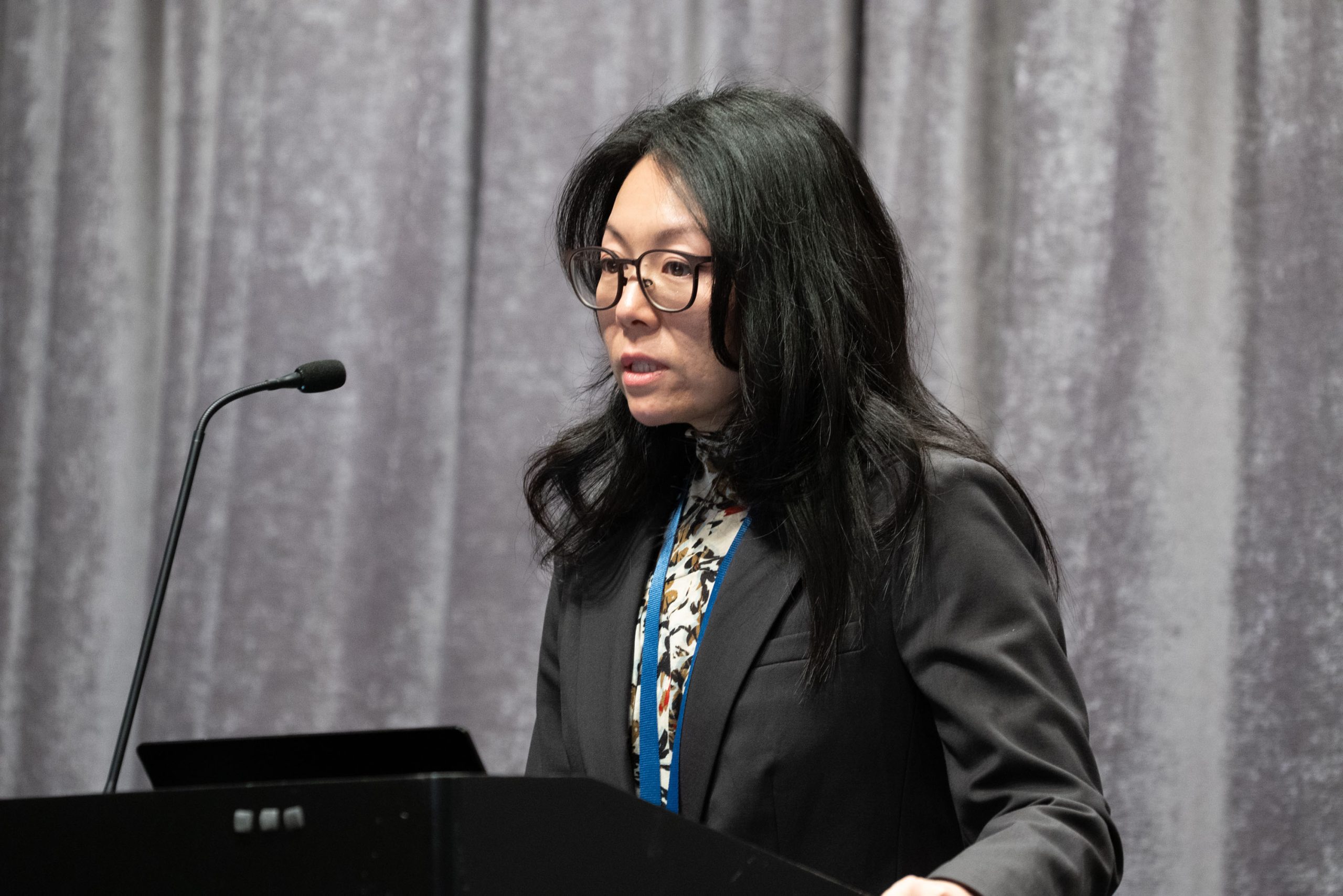Speaker at podium addressing audience during conference.