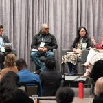 Panelists seated on stage during a conference discussion.