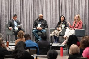 Panelists seated on stage during a conference discussion.