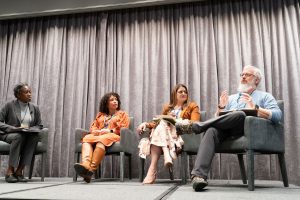 Panelists seated on stage during a conference discussion.