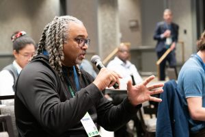 Man speaking with microphone during audience Q&A.